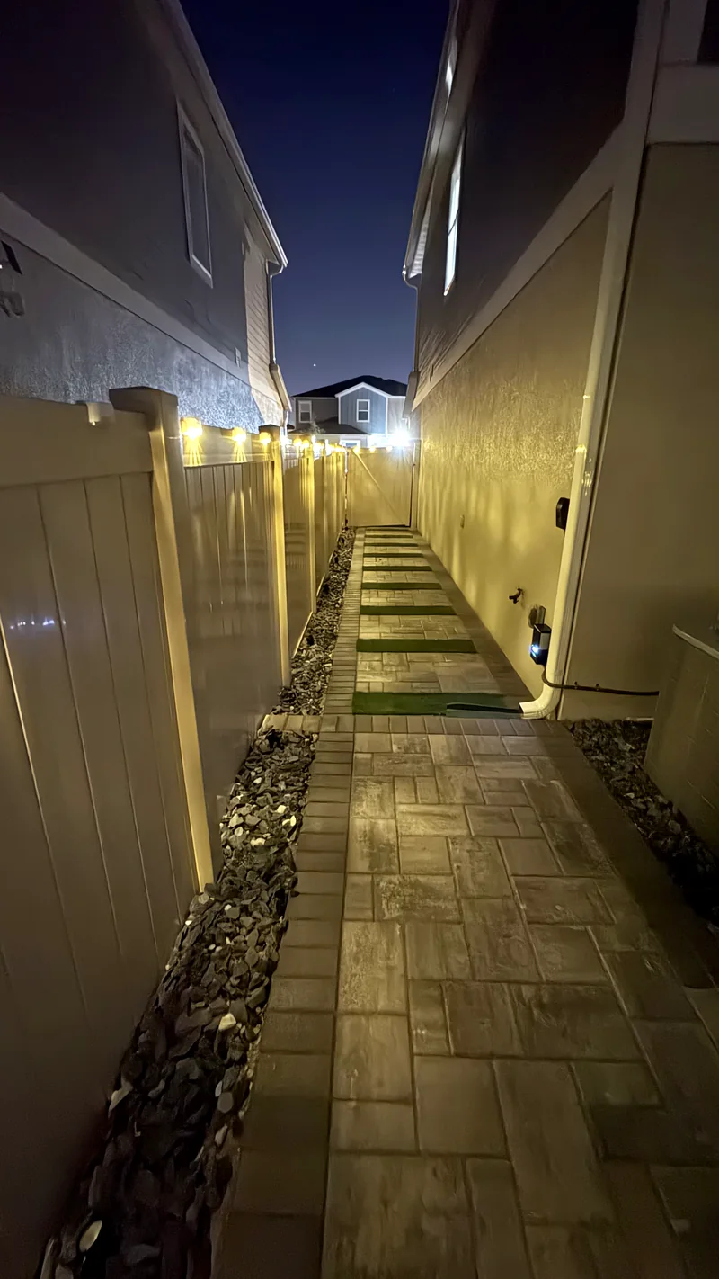 Paver walkway down the side of the house, fence lights on